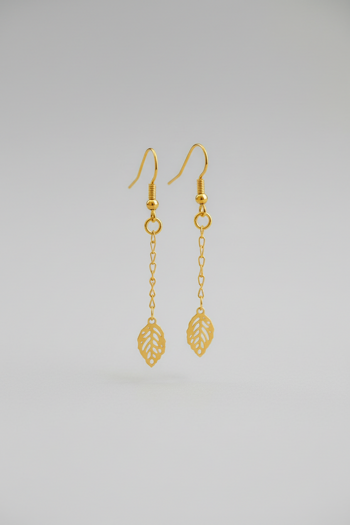 Gold earrings with leaf designs on a light gray background