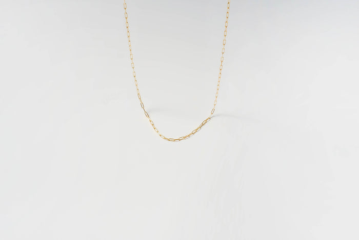 The Adelene Paperclip Chain by LLUME Jewelry features delicate gold-plated oval links, elegantly displayed against a plain white background.