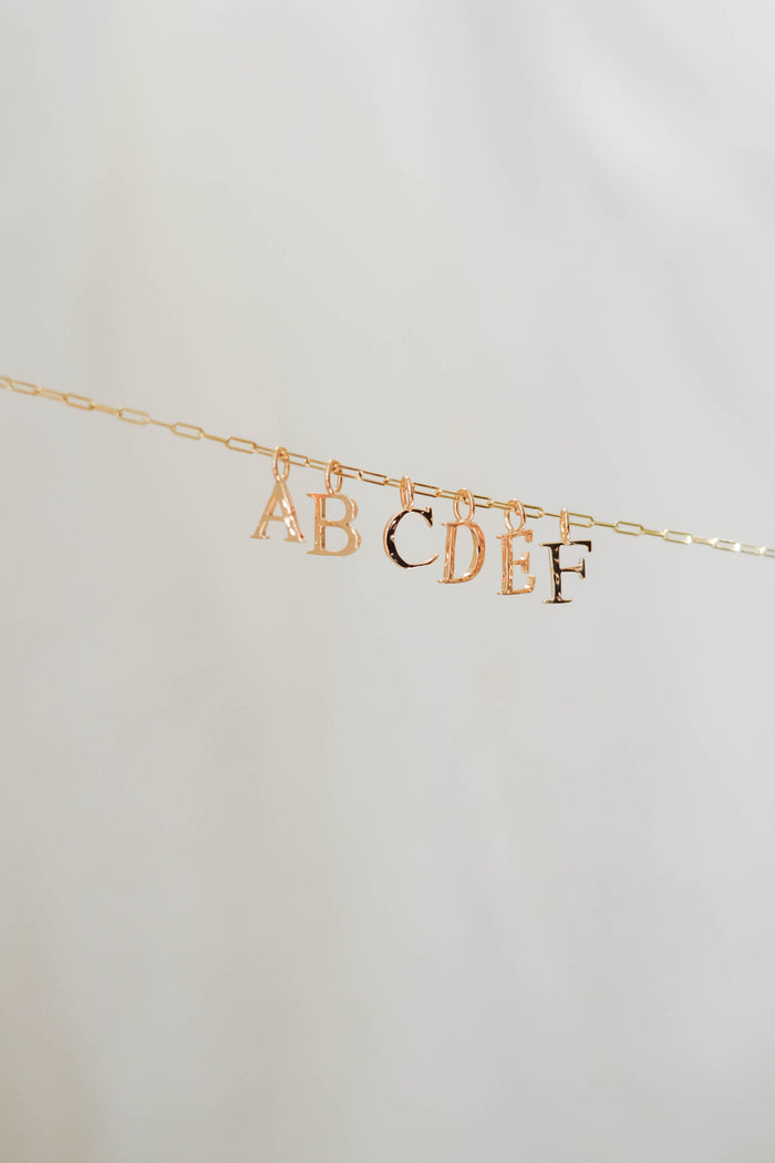 The LLUME Jewelry Alphabet Charm Necklace features gold A-F letter charms on a delicate gold chain, offering a stylish and customizable piece for personalized jewelry lovers.