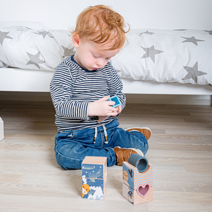 Child playing with wooden blocks on a wooden floor.