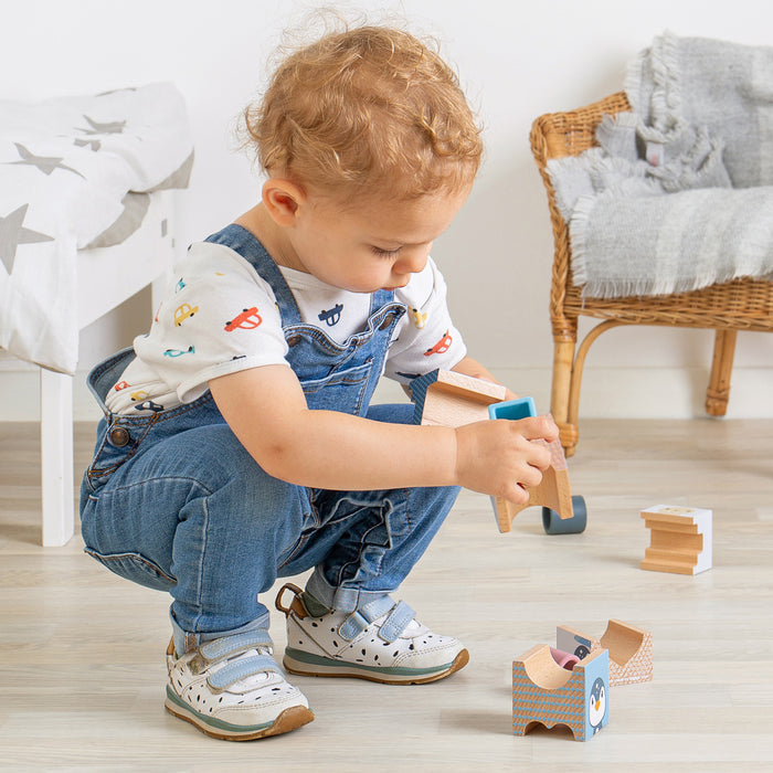 Child playing with wooden toys on a light wood floor.