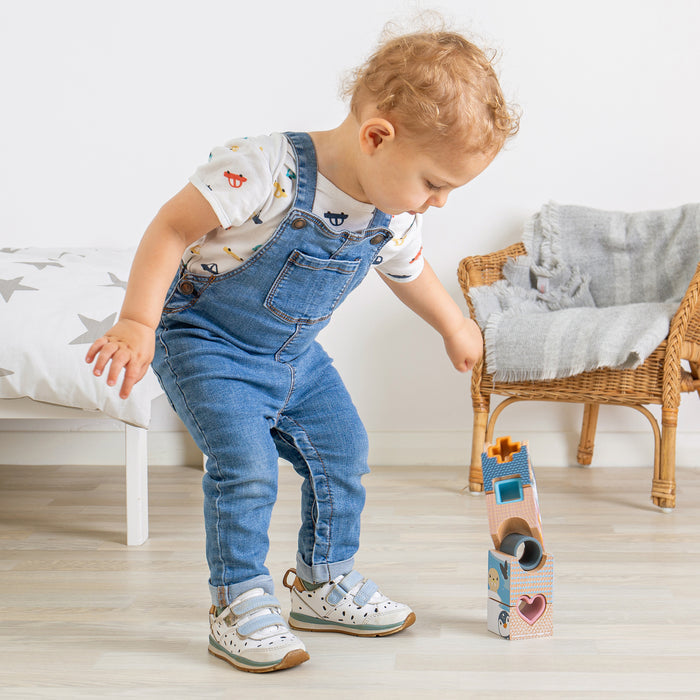 Child playing with a toy in a room with a white wall and wooden floor.