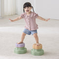 Child standing on two colorful step stools in a room with a white floor and light-colored walls.