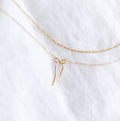 The Bow Daily Set by LLUME Jewelry features two delicate gold necklaces: a classic chain and the Colette Necklace with a charming bow pendant—perfect for graceful, effortless layering.