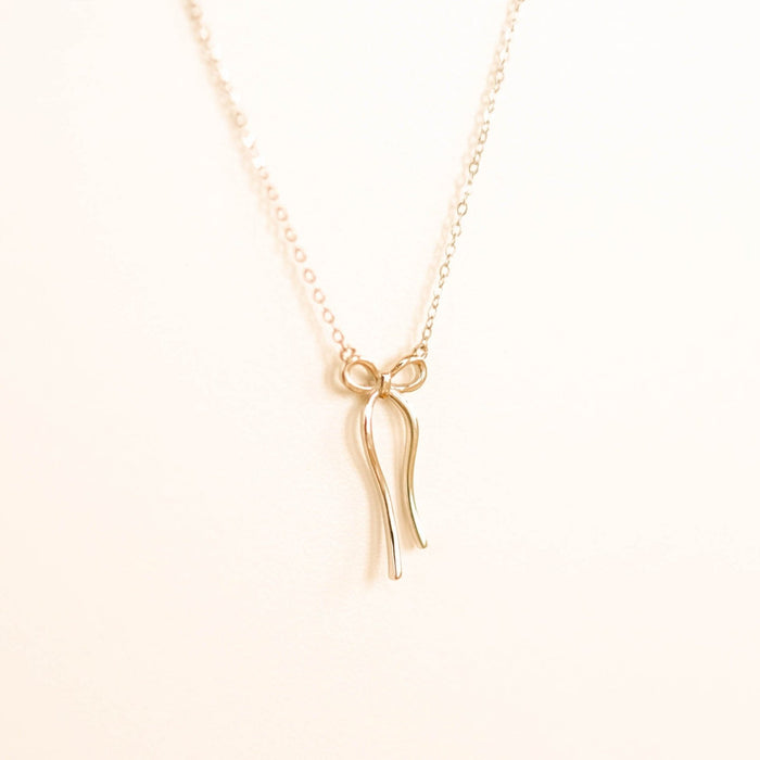 The LLUME Jewelry Bow Necklace is a limited edition gold-plated piece featuring a fine chain and minimalist bow pendant, shown against a plain light background.