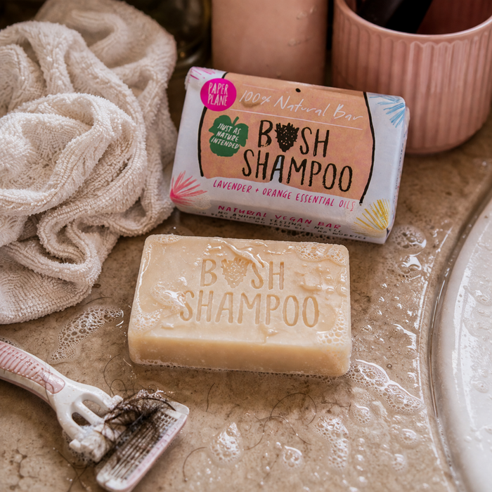 Paper Plane Bush Shampoo vegan bar with soap suds razor and bathroom countertop setting
