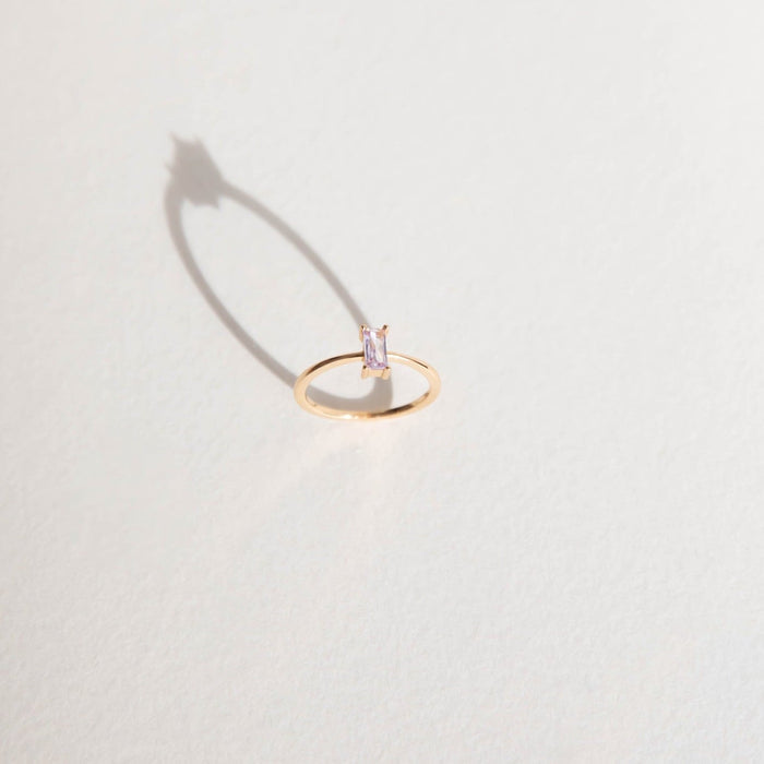 The Celia Ring by LLUME Jewelry features a rectangular, light purple amethyst gemstone on a delicate gold-filled band, perfect for stacking and styling with your favorite pieces.