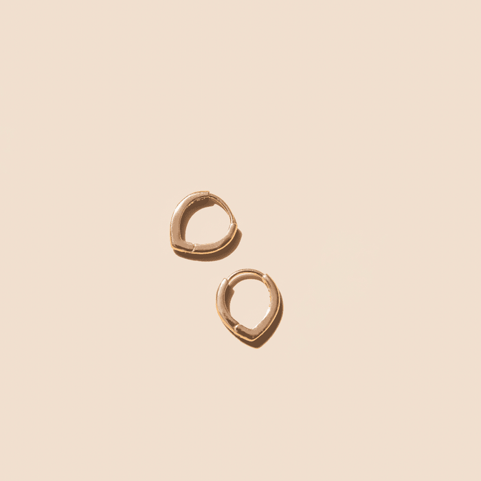 The LLUME Jewelry Classic Pointed Hoop earrings, crafted in 18k gold filled, are seen on a light beige background. These small hoops feature a smooth, polished finish and a simple, minimalistic design.