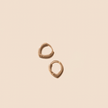 The LLUME Jewelry Classic Pointed Hoop earrings, crafted in 18k gold filled, are seen on a light beige background. These small hoops feature a smooth, polished finish and a simple, minimalistic design.