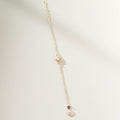 The Cyra Bracelet by LLUME Jewelry is a gold-plated sterling silver piece with a sun-shaped charm and a central white stone, elegantly displayed on a light textured surface with soft shadows.