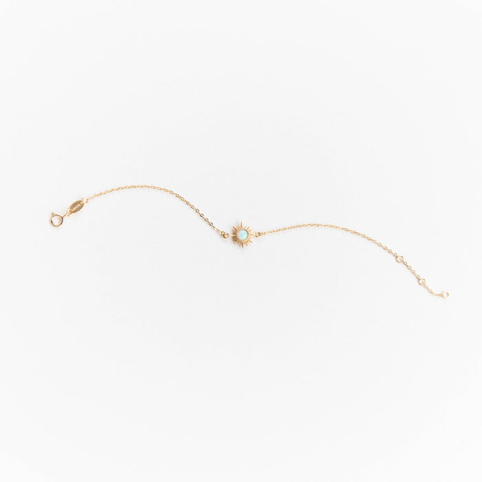 The Cyra Bracelet by LLUME Jewelry is a gold-plated sterling silver piece with a tiny opal sunburst charm at the center, shown on a plain white background.