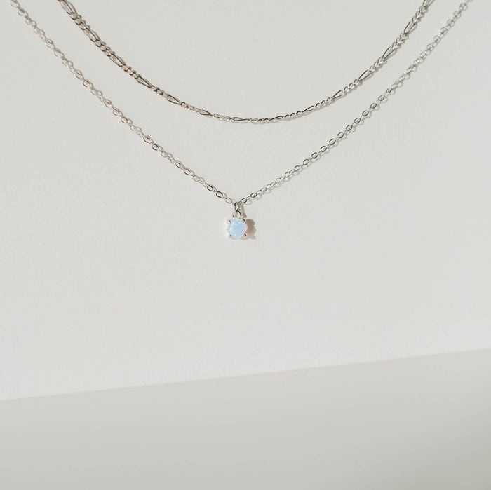Two delicate pieces of silver jewelry by LLUME Jewelry's Daily Set Silver hang against a white background; the lower chain features a small round pendant reflecting soft blue and white hues.