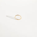 The Dune Ring by LLUME Jewelry is a simple, thin 14k gold-filled band with a subtle organic shape, shown on a white surface casting a gentle shadow—ideal for stacking or easy everyday wear.