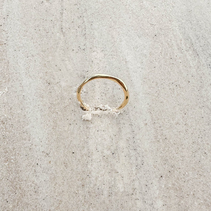 The Dune Ring by LLUME Jewelry is a 14k gold-filled band, partially visible in light-colored sand—ideal for daily wear or stacking with your other favorite rings.