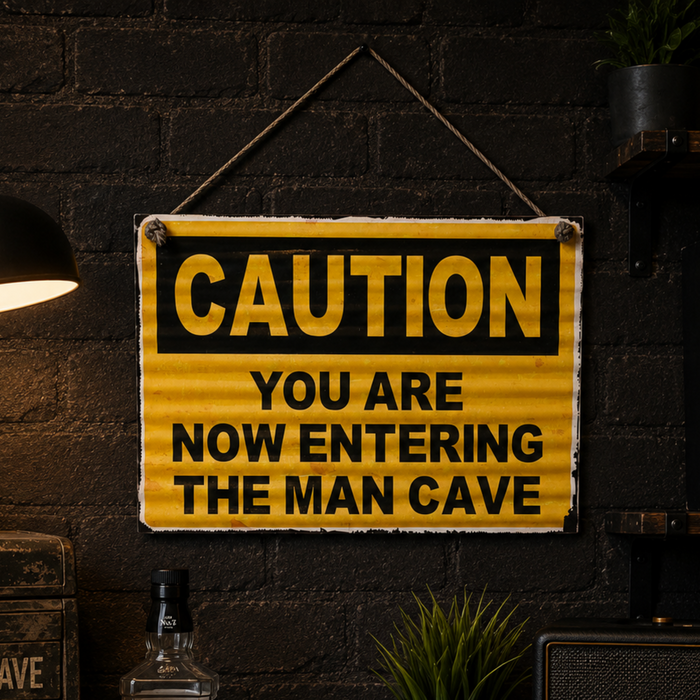 Vintage style caution man cave tin sign hanging on a dark industrial wall with warm lighting and masculine decor.