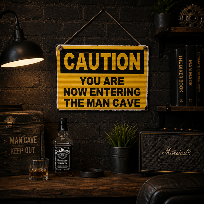 Caution You Are Now Entering The Man Cave corrugated tin sign displayed in a rustic industrial style man cave with whiskey, books and warm ambient lighting.