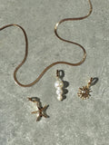 The LLUME Jewelry Every Occasion Set features a gold snake chain necklace on a gray textured surface, accompanied by three interchangeable charms: a starfish, white pearl cluster, and sunburst design.