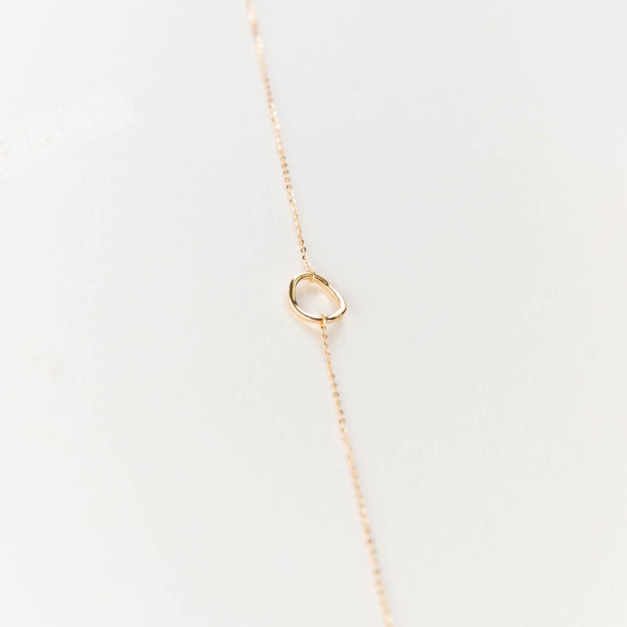 The Everything, In Time Necklace by LLUME Jewelry features a delicate gold chain and a simple organic circle pendant, shown on a light neutral background.