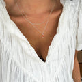 A person wearing a crinkled white V-neck blouse and two delicate silver necklaces, including LLUME Jewelry's Fate Daily, creates an effortlessly chic jewelry set.