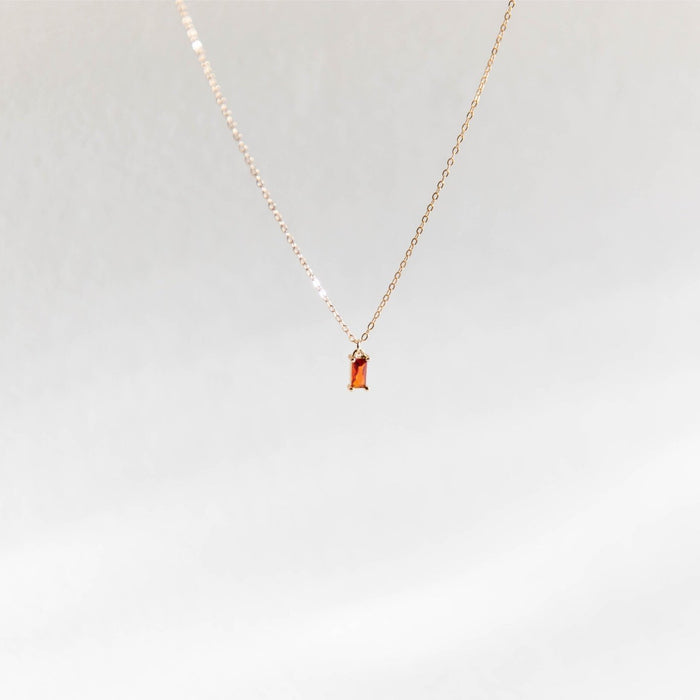 The Fate Necklace by LLUME Jewelry features a delicate gold plated sterling silver chain and a small rectangular orange gemstone pendant, elegantly showcased against a simple light background.