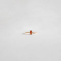 The Fate Ring by LLUME Jewelry features a delicate 14k gold-filled band with a rectangular red stone, showcased on a plain, light gray background.