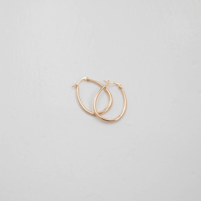 The Fireside Hoops by LLUME Jewelry, vintage gold hoop earrings with a leverback closure, rest on a plain light gray surface.