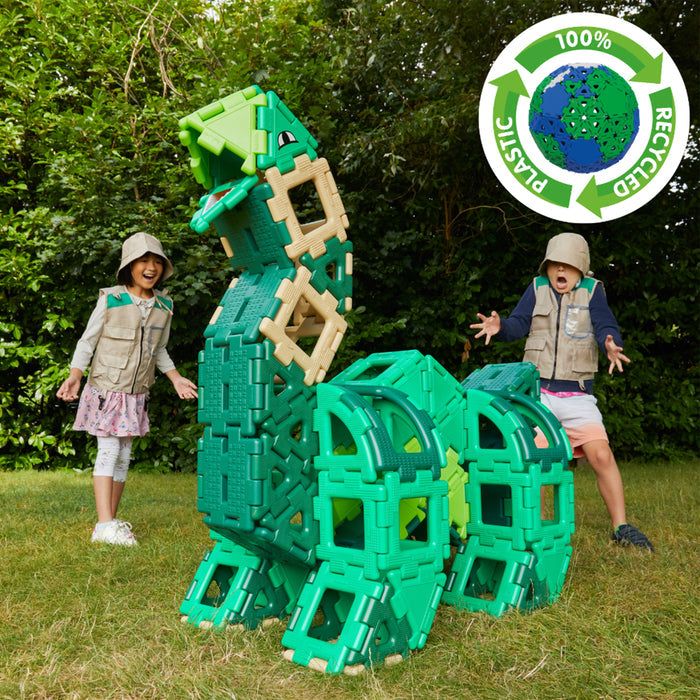 Children playing with green dinosaur building blocks in a grassy area, with a recycling logo in the corner.