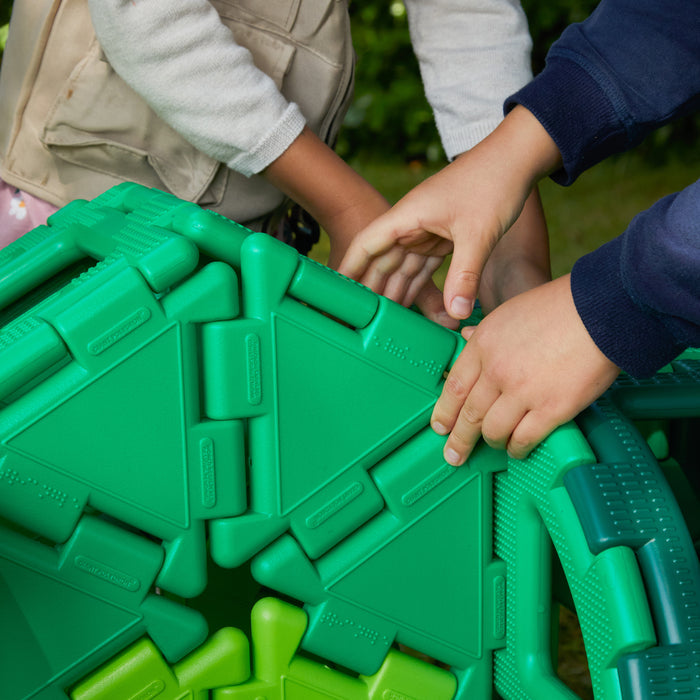 Children playing with green plastic blocks outdoors