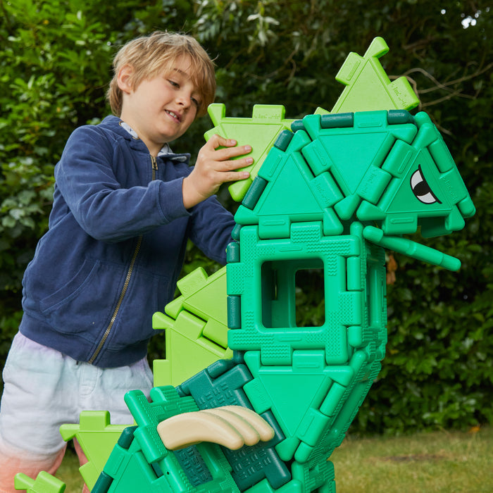 Child playing with a green toy structure outdoors