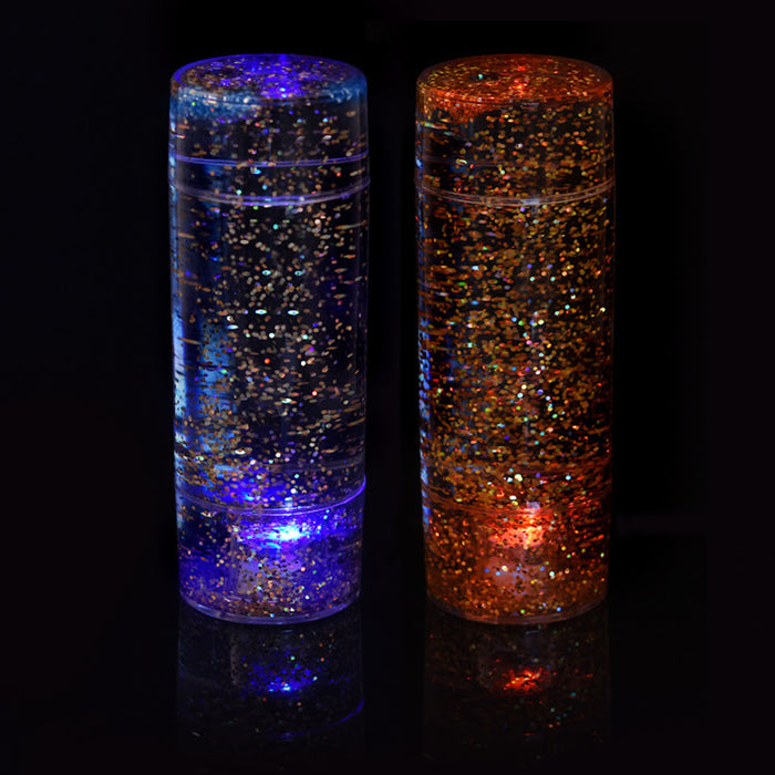 Two cylindrical containers filled with glitter and light on a black background