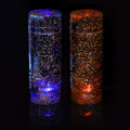 Two cylindrical containers filled with glitter and light on a black background