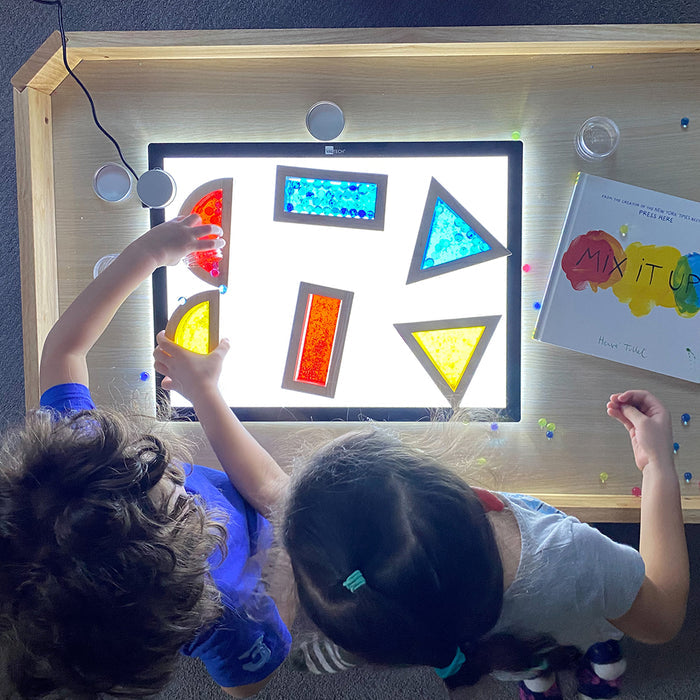 Kids using transparent water blocks on light table