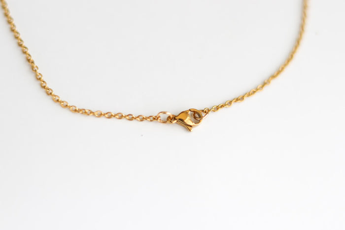Gold cross chain necklace for men on a white shirt with a plain background