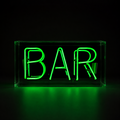 Green BAR neon sign in clear acrylic case glowing against a dark black background with green reflections underneath