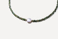 The Isla Necklace by LLUME Jewelry features handcrafted small round green natural stones and a central larger white pearl, shown on a white background.