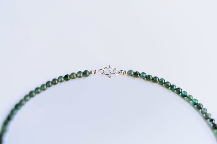 A close-up of the LLUME Jewelry Isla Necklace, featuring green natural stone beads and a silver hook clasp, displayed on a plain white background.