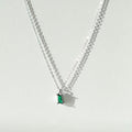 The Kismet Necklace Silver by LLUME Jewelry features a thin sterling silver chain and a rectangular green gemstone pendant, ideal for dainty jewelry lovers. It creates a soft shadow on a light background.