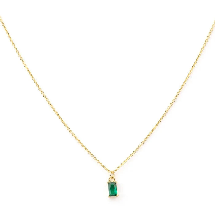 The Kismet Necklace features a simple and elegant gold-plated chain with a small, rectangular emerald green charm pendant set in gold, beautifully centered on the delicate chain.