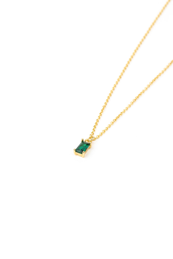 The Kismet Necklace features a gold plated chain and a small emerald green charm pendant, shown against a white background.