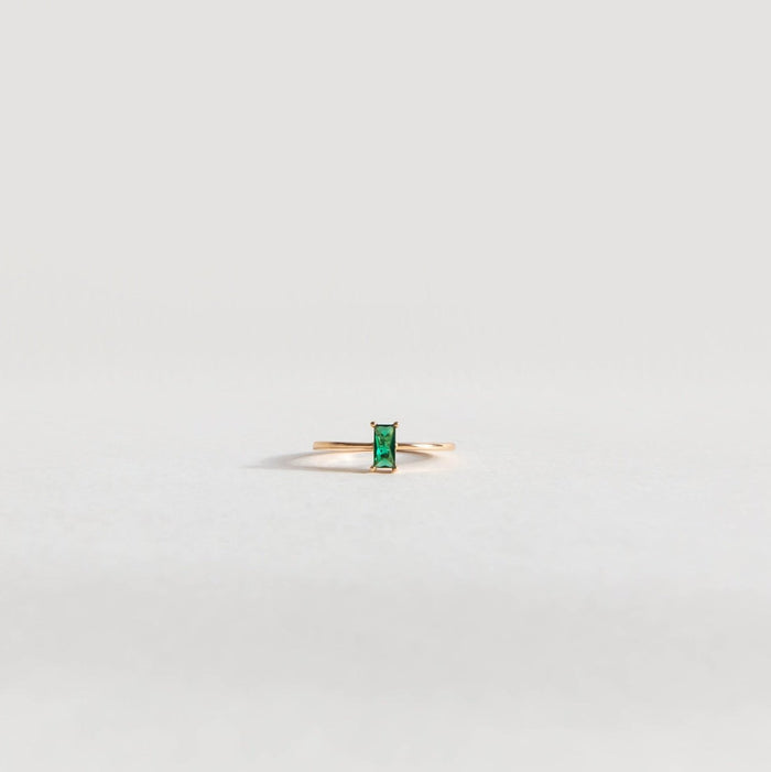 The Kismet Ring by LLUME Jewelry features a vertical rectangular emerald green stone set in delicate 14k gold-filled metal, shown against a plain light gray background.