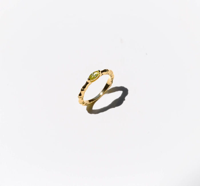 The Limon Ring by LLUME Jewelry, a gold-plated 925 sterling silver piece featuring a textured band and lemon yellow gemstone, is shown on a white background with a soft shadow to the lower right.