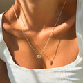 Wearing a white ribbed tank top, a person shines in warm sunlight, showcasing the LLUME Jewelry Love Heart Necklace—a delicate gold plated heart pendant.