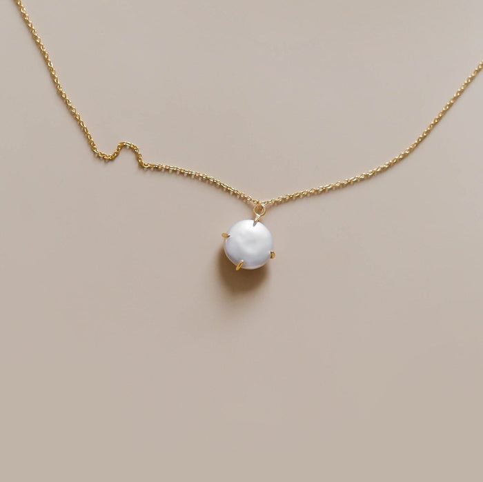 The Lovegood Necklace by LLUME Jewelry is a delicate gold vermeil piece with a single round white pearl pendant in a minimalist prong setting, shown against a plain beige background.