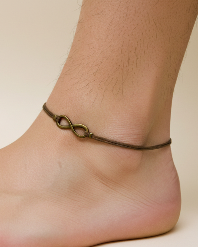 Ankle bracelet with infinity charm on a foot against a neutral background