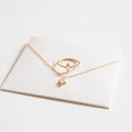 The LLUME Jewelry Moment Set features a delicate gold necklace with a heart pendant and a matching ring with a tiny diamond, both displayed on a white card against a white background. Perfect for stacking.