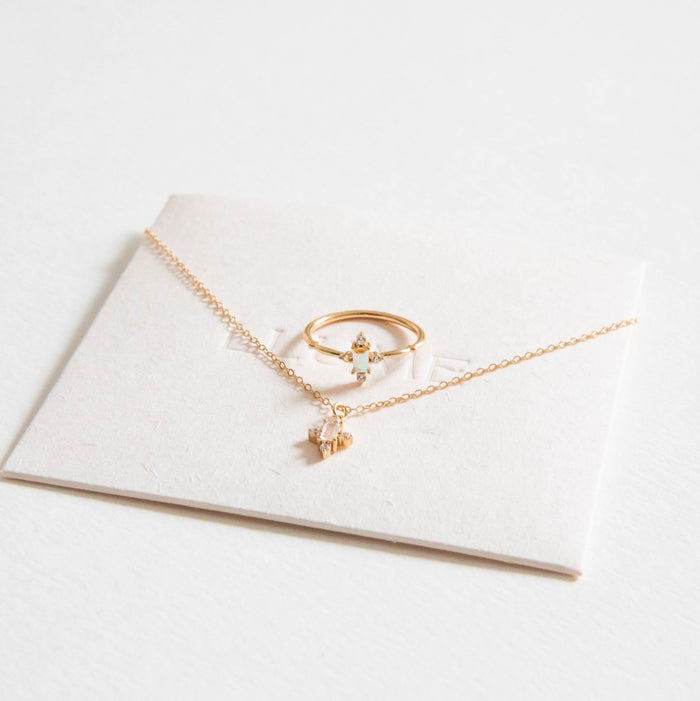 The LLUME Jewelry Moment Set features a delicate gold necklace with a heart pendant and a matching ring with a tiny diamond, both displayed on a white card against a white background. Perfect for stacking.