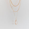 LLUME Jewelry’s New Era Bundle features three delicate gold layered necklaces, one with a clear teardrop gemstone pendant, displayed against a plain light background—an ideal choice to elevate your winter wardrobe.