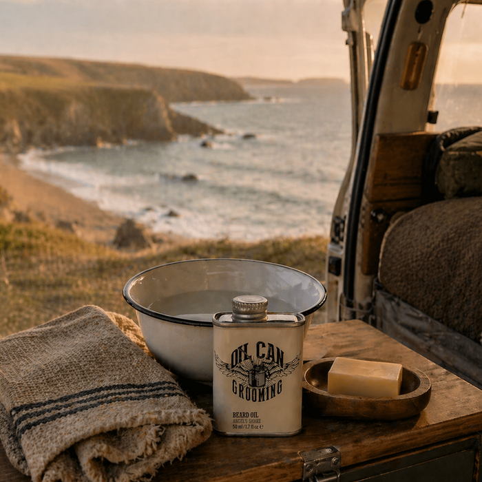 Oil Can Grooming beard oil with wash bowl, soap and towel in a camper van setting overlooking the coast at sunset