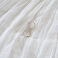 LLUME Jewelry’s Prosecco Beaded Hoops Silver are displayed on a soft, white, textured fabric with gentle folds.