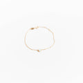 The Sardinia Bracelet by LLUME Jewelry features a delicate gold plated sterling silver chain with a small white stone centerpiece, shown on a plain white background.